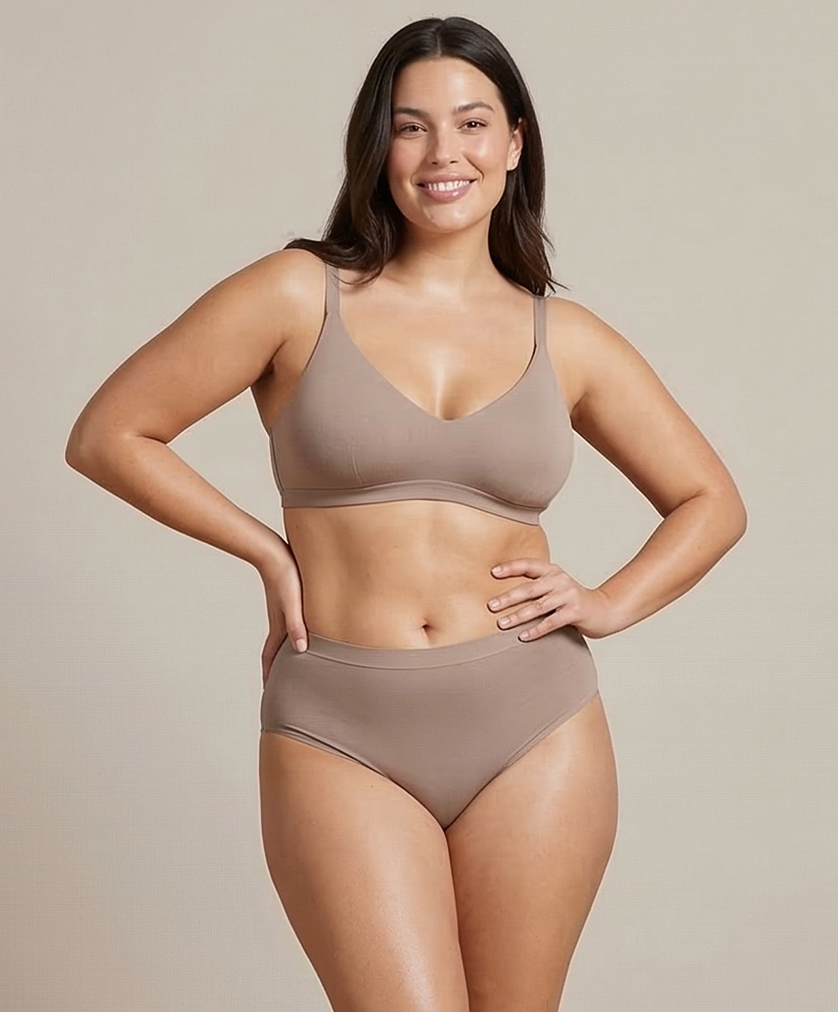 Model wearing beige intimate apparel, smiling confidently.