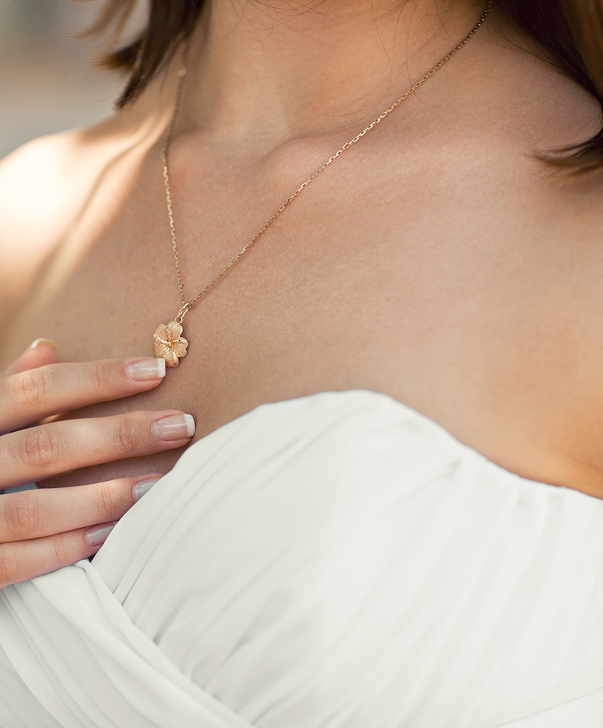 Woman wearing a flower necklace and white dress.
