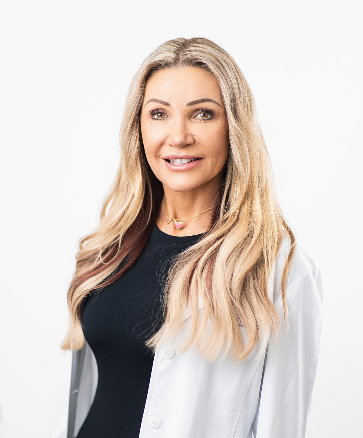 Professional woman in white lab coat, smiling.