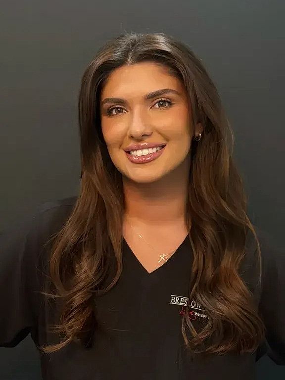 Smiling woman in professional attire, dark background.