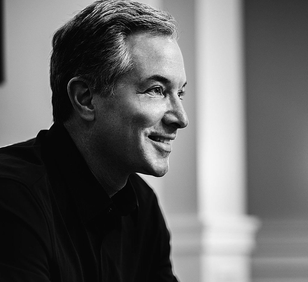 Smiling man in black and white portrait.