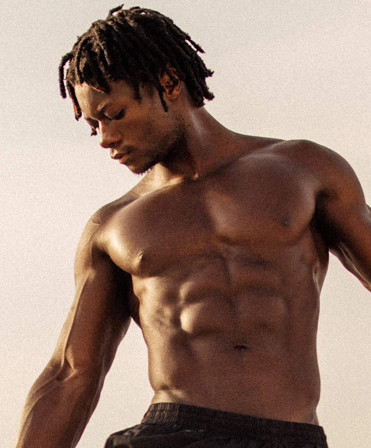 Athletic man with dreadlocks posing outdoors.