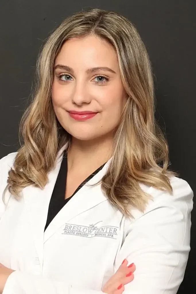 Woman in white coat, smiling confidently.