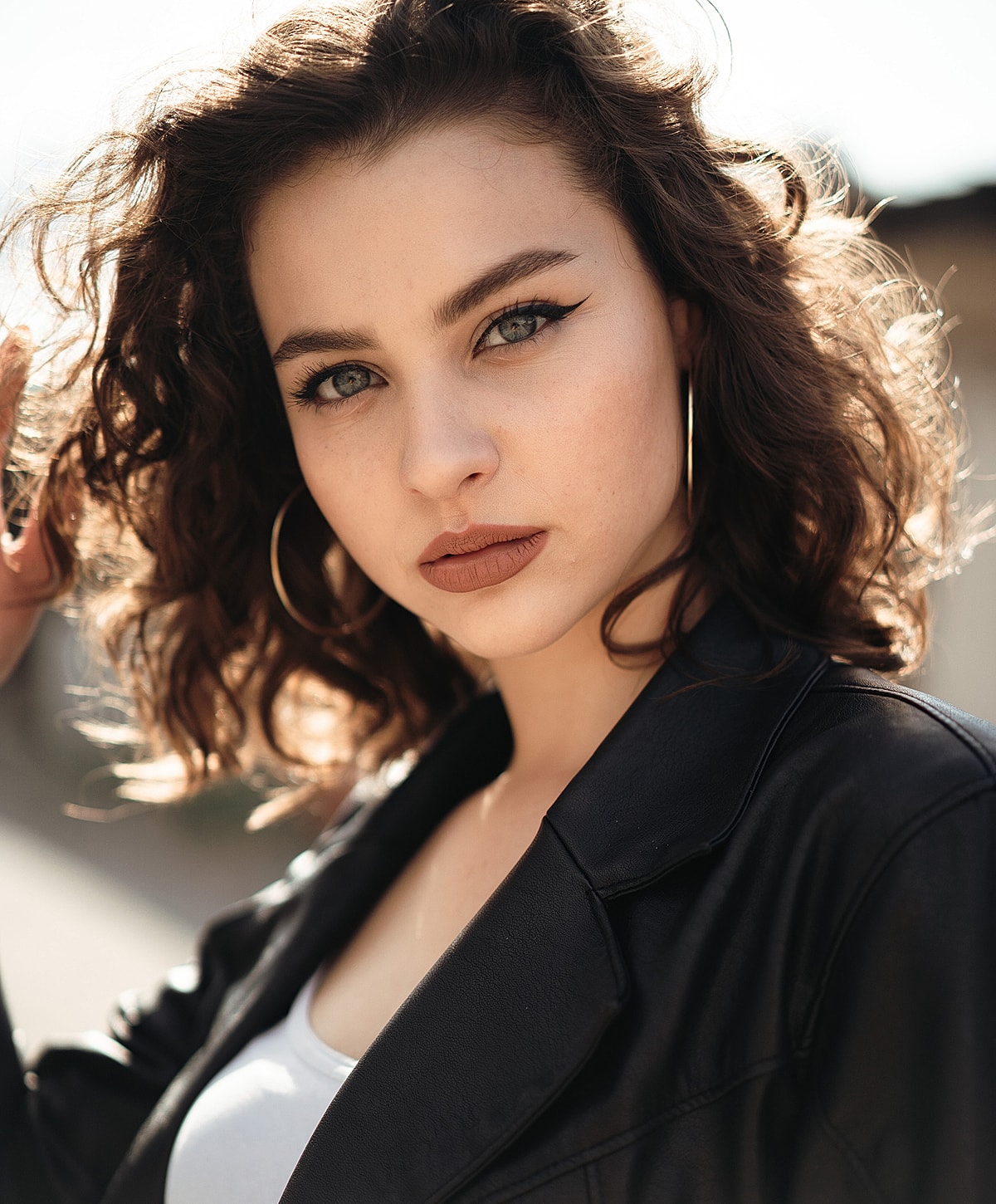 Young woman with curly hair and bold makeup.