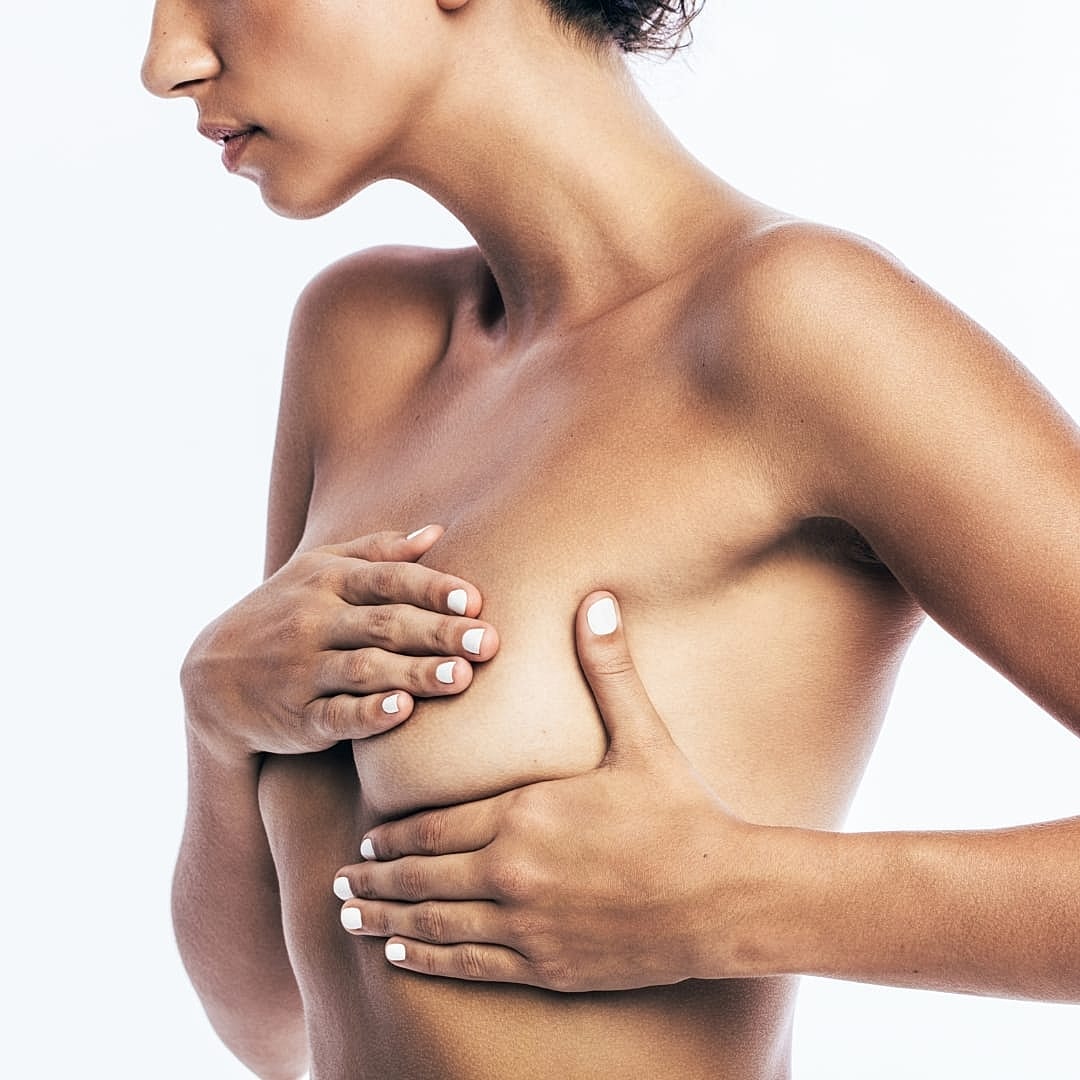 Woman posing, covering chest in soft lighting.