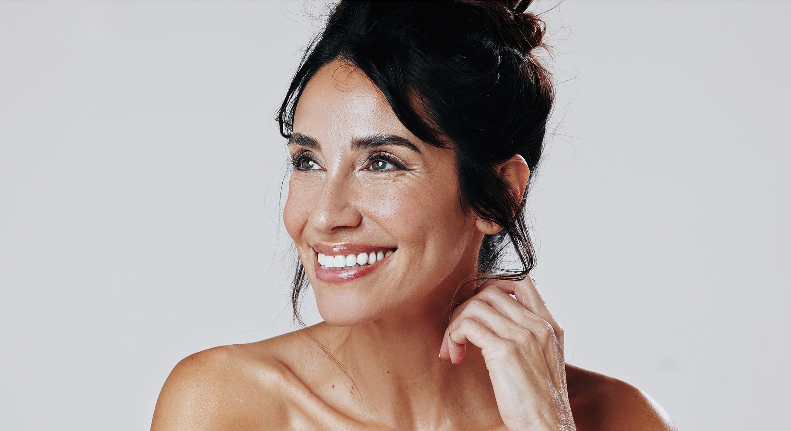 Smiling woman with dark hair on light background