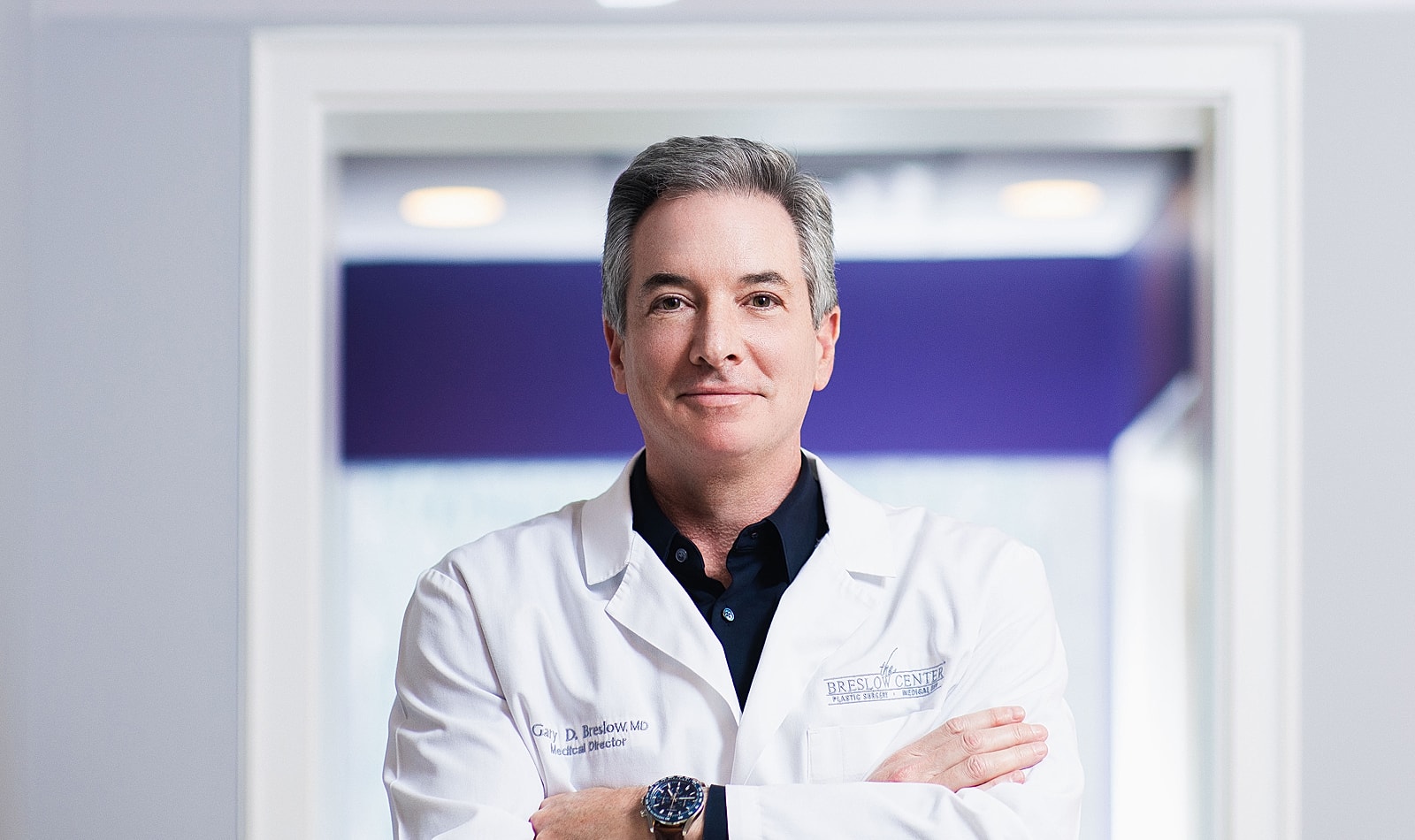 Male doctor in white coat, smiling confidently.