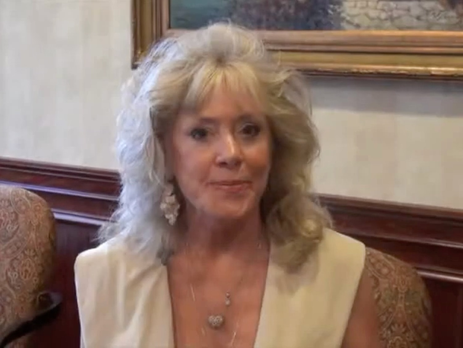 Woman with blonde hair in elegant attire.